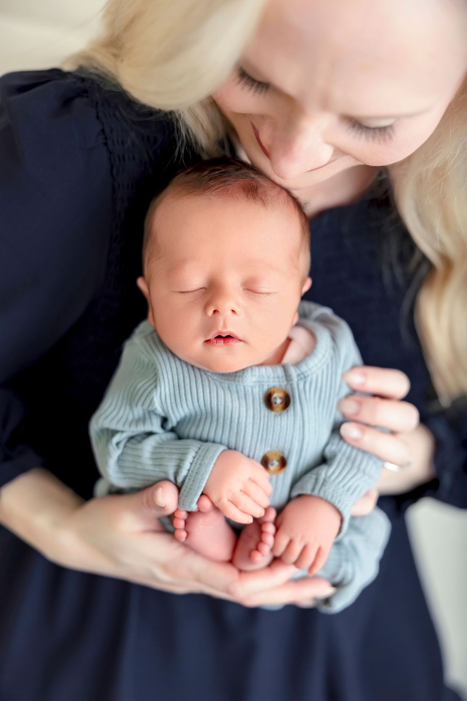 Mother holding her sleeping newborn son during a studio newborn session in Clear Lake, Iowa.