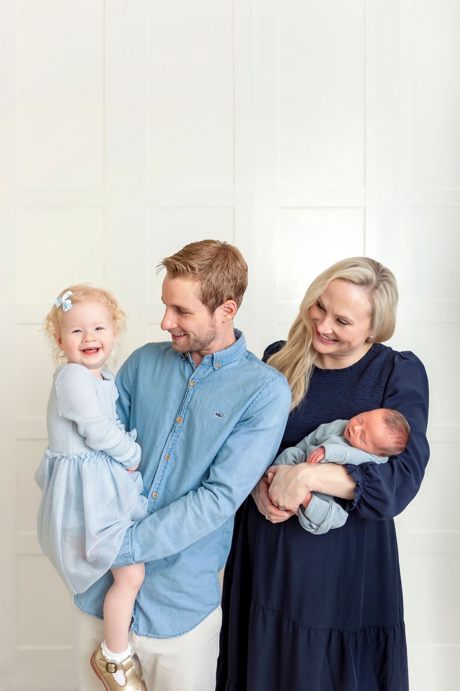 Family of four posing together during a studio newborn session in Clear Lake, Iowa.