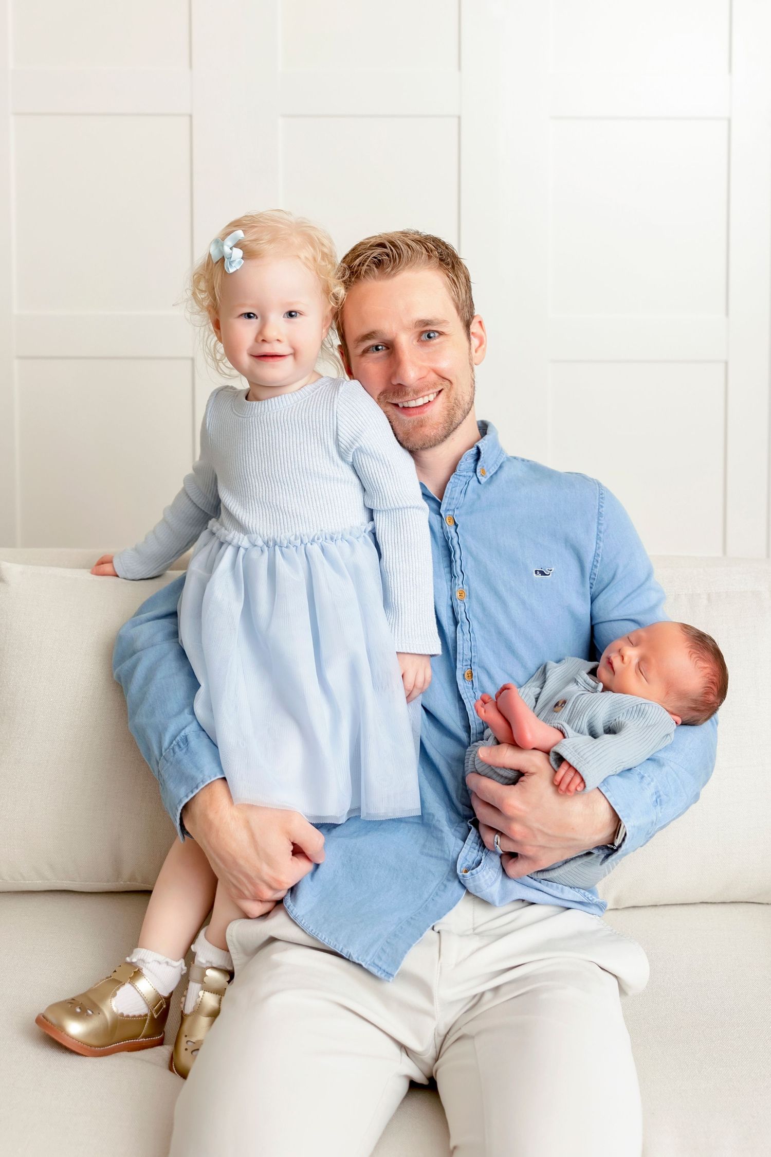 Father holding his newborn son while smiling with his daughter during a studio newborn session.