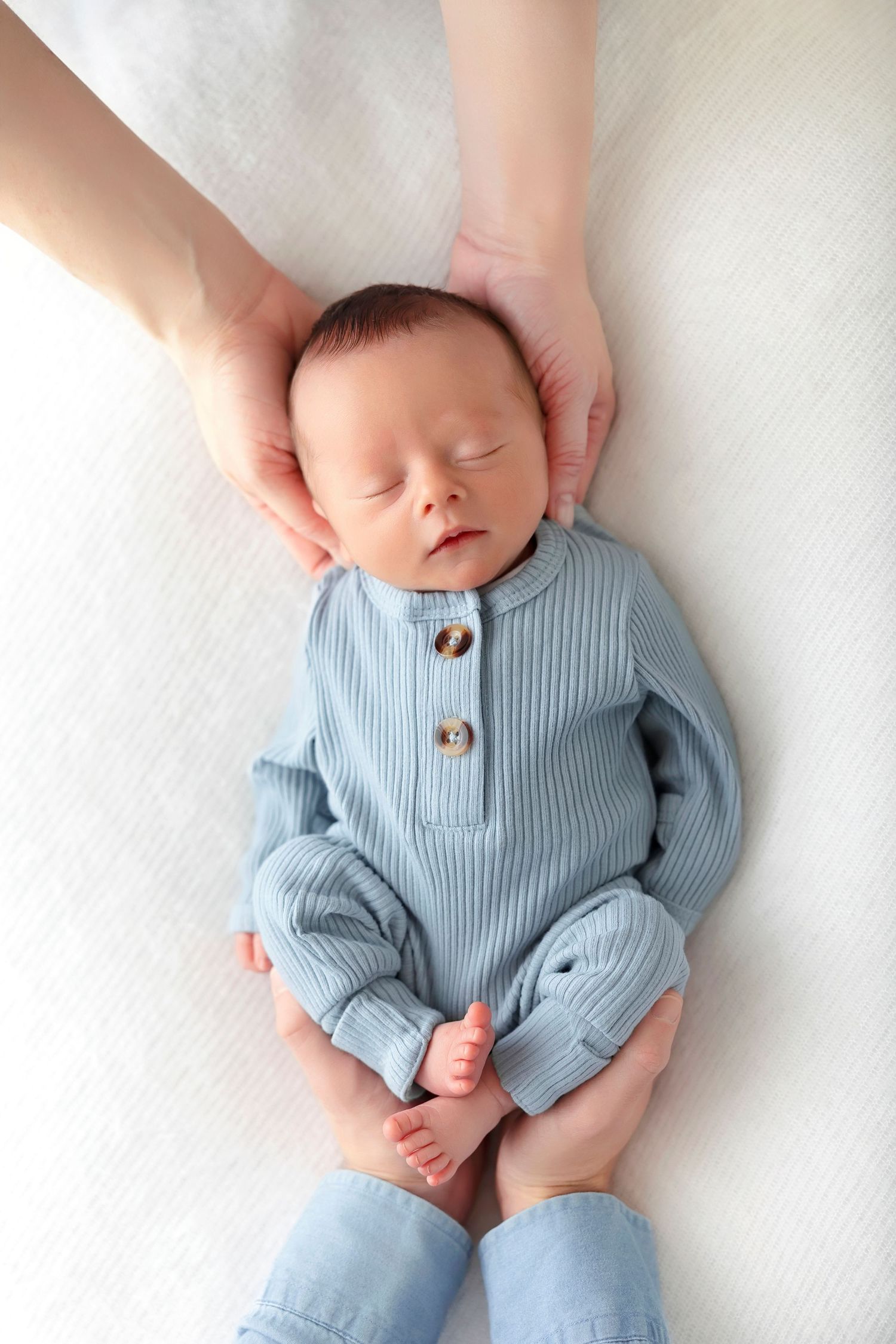 Overhead portrait of a sleeping newborn baby boy wrapped in blue during a studio newborn session.