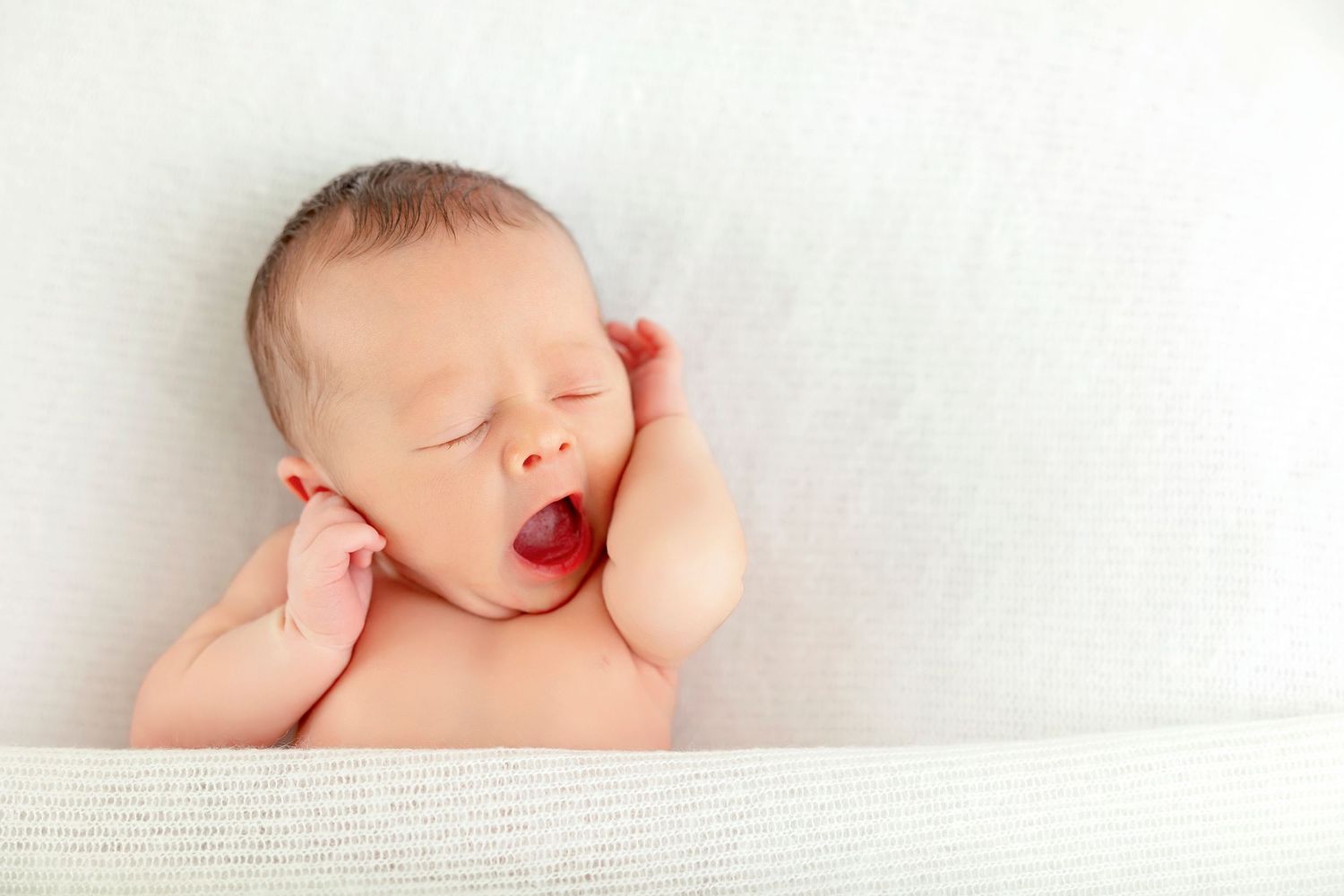 Close-up portrait of a yawning newborn baby during a studio newborn photography session.