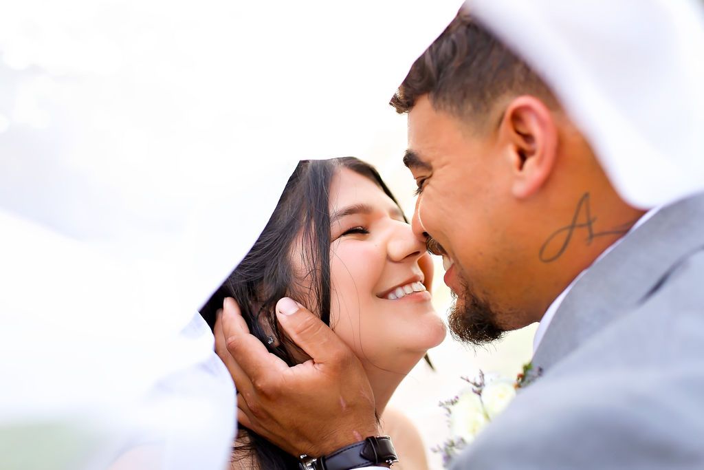 Bride  smiling on wedding day while groom holds her face