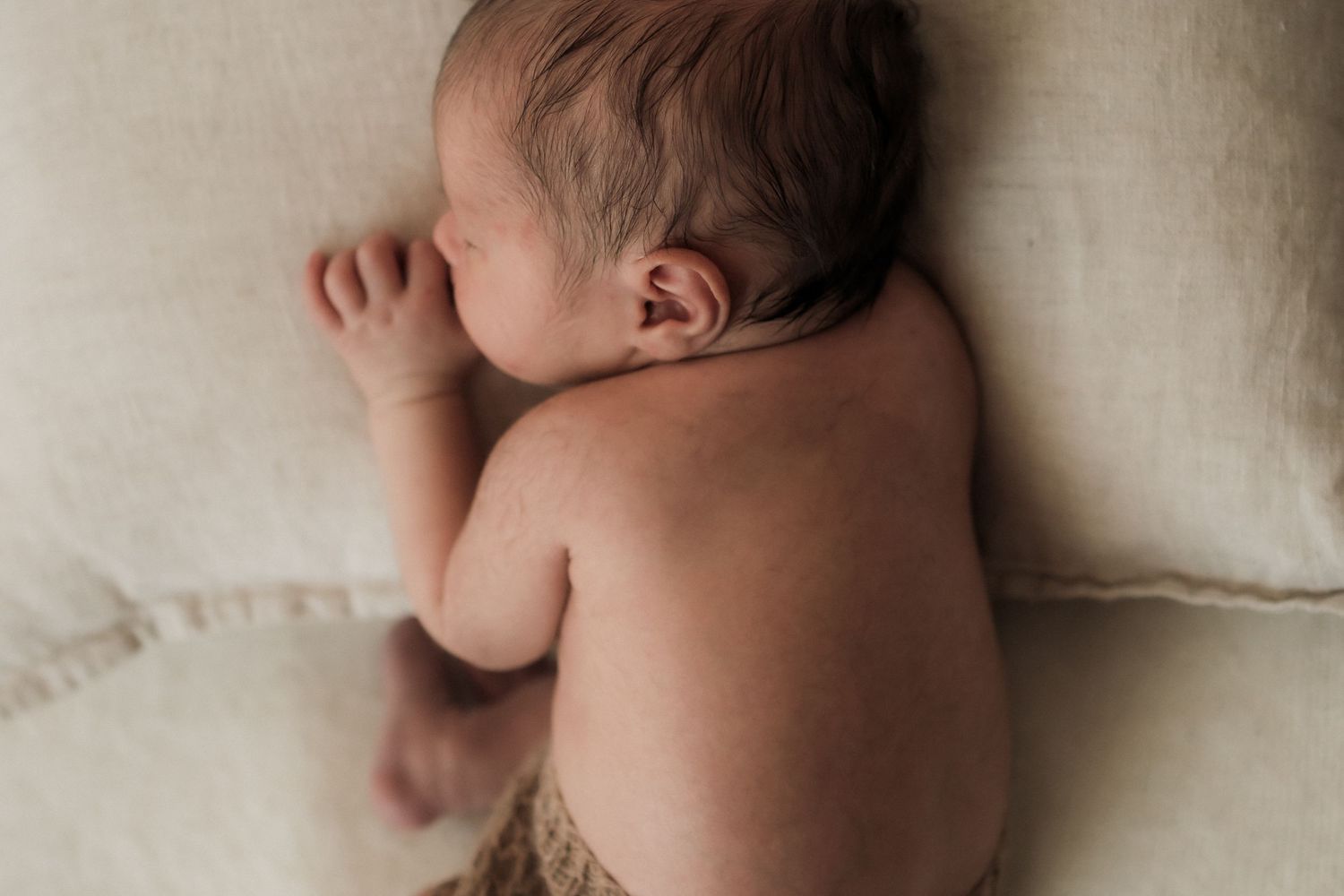 Peaceful newborn baby sleeping on a soft cream pillow, captured from above in a serene portrait photo in the Yarra Valley, Victoria