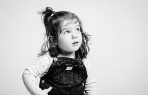 Black and white portrait series showing candid childhood expressions and poses in overalls.