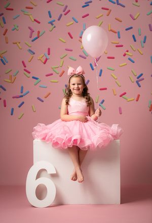 A sweet birthday portrait series showing a pink party dress against a pink backdrop with confetti and white number 6 prop.