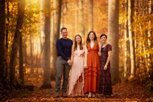 A group stands in a sunlit autumn forest path with golden foliage creating a warm, ethereal atmosphere.