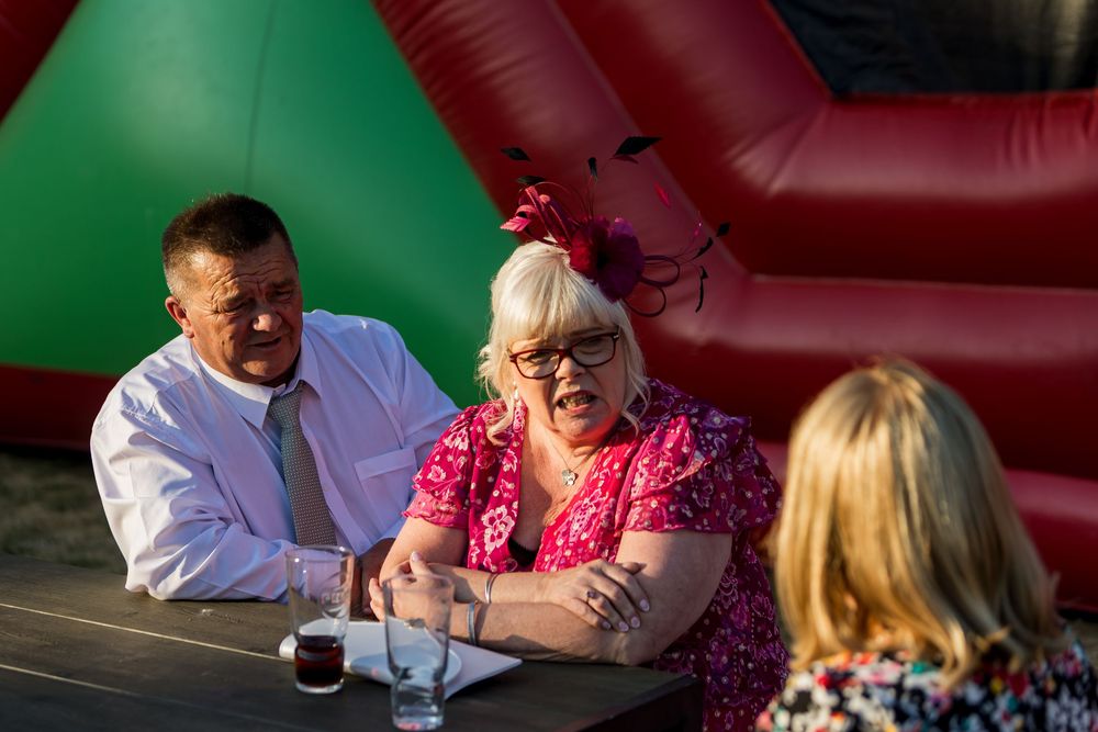 Two guests chatting at an outdoor wedding reception near a colorful inflatable.