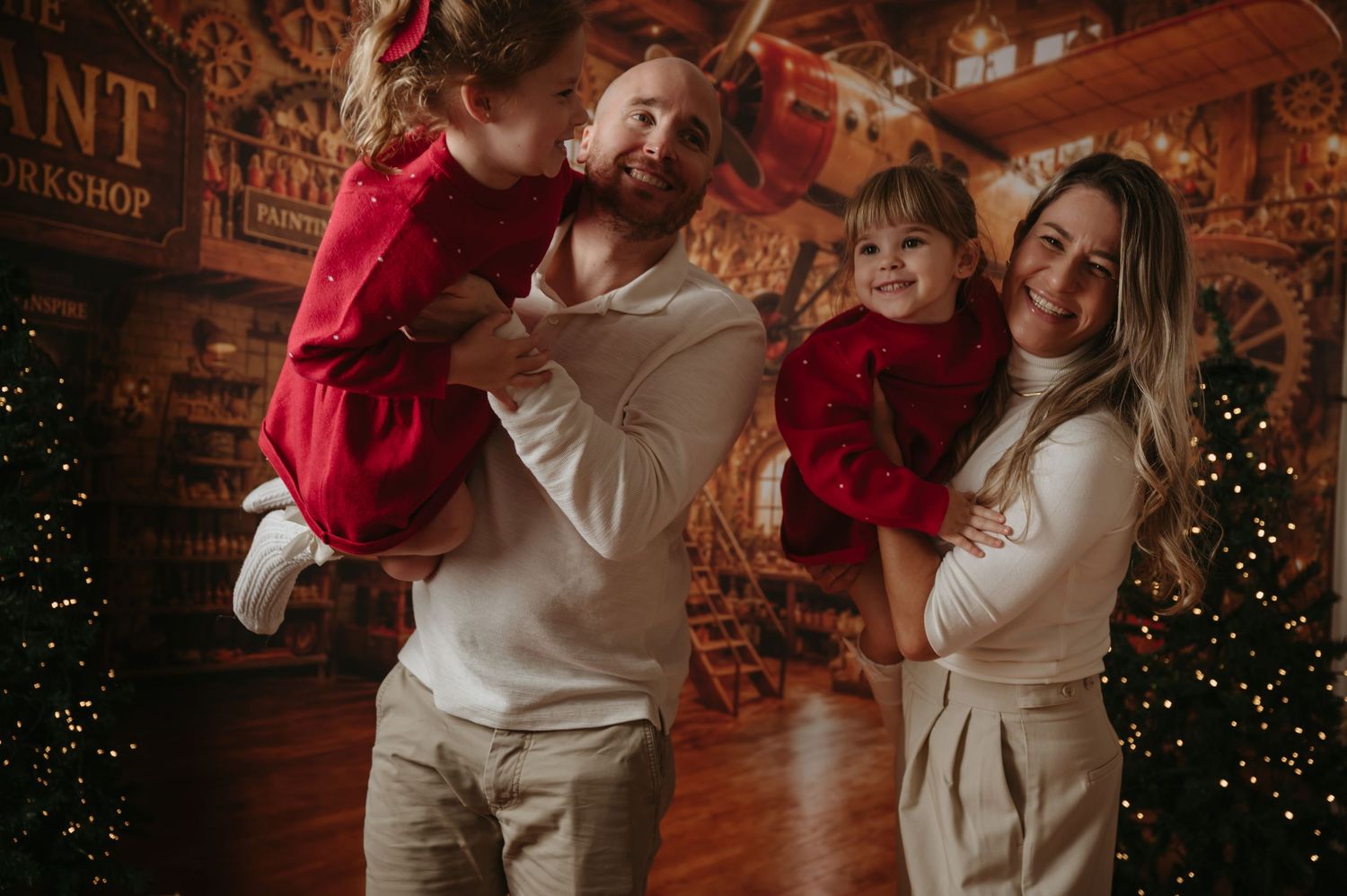 Parents smiling with their two children during a previous Christmas photography session.