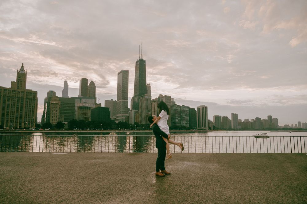 Couple dancing romantically by Chicago skyline waterfront on a cloudy day with city skyscrapers in background.