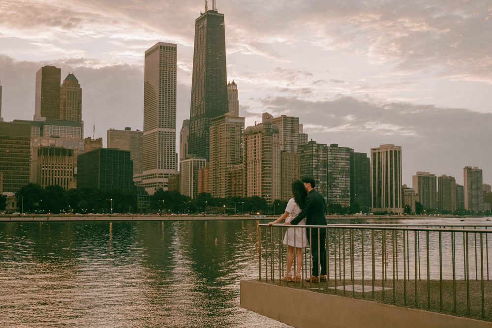 Couple embracing on a pier overlooking the Chicago skyline with the Willis Tower at sunset.