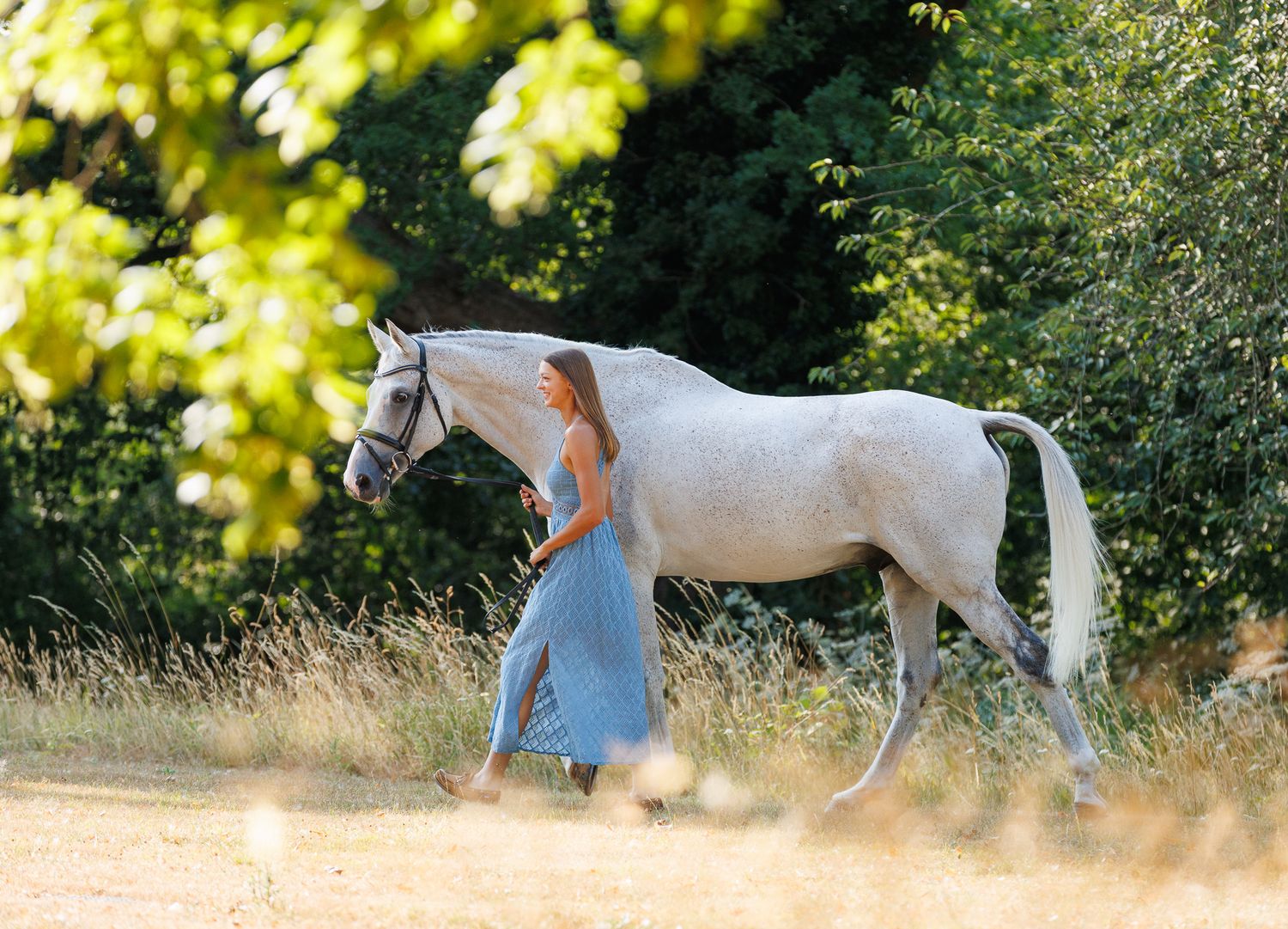 A horse and its rider enjoy an outdoor photoshoot session near rustic wooden fencing on a sunny day.