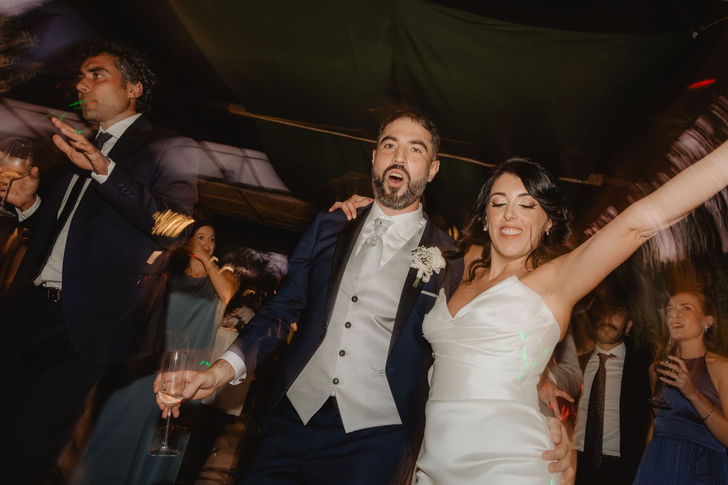 Marco ed Elena festeggiano insieme agli invitati con le braccia alzate.