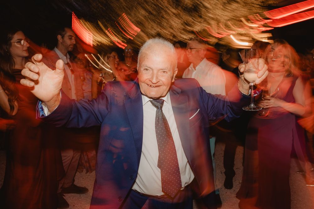 Un invitato balla durante il ricevimento, tra luci calde e movimento.