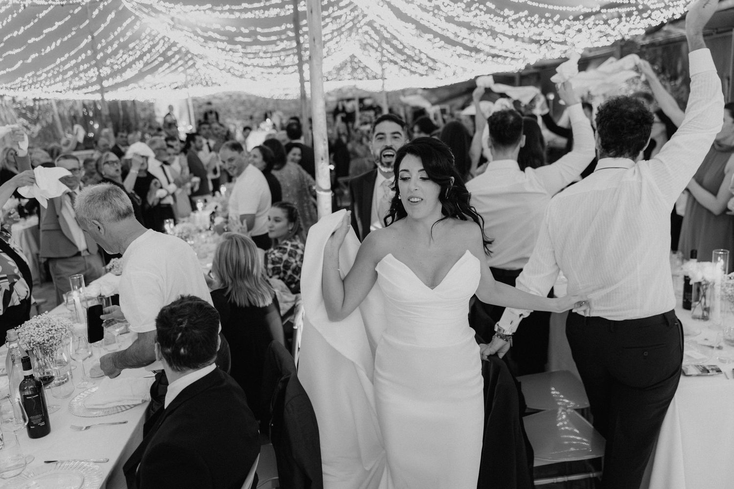Gli sposi e gli invitati ballano insieme, in bianco e nero.