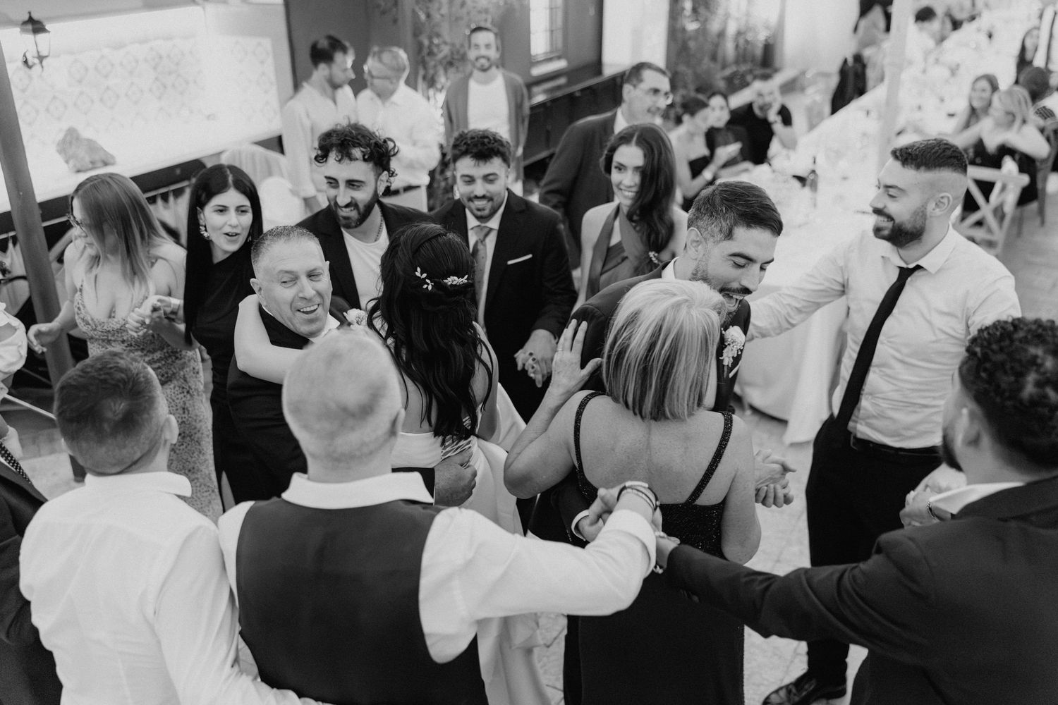 Gli invitati si stringono in un abbraccio durante la festa, in bianco e nero.