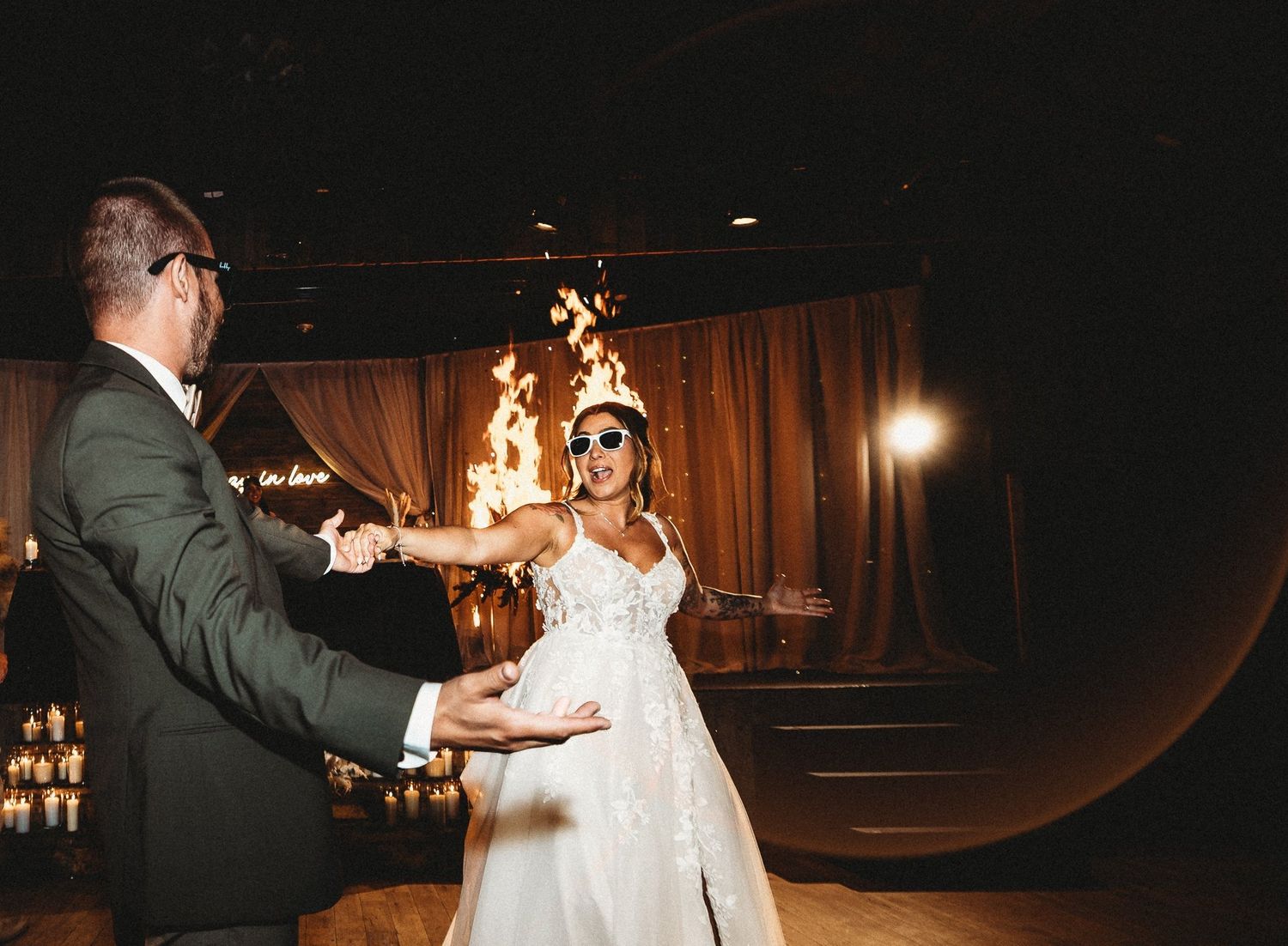Bride and groom in sunglasses sharing a fiery first dance with flames behind them at the reception