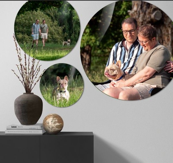 Three circular photo prints on a gray wall show a French bulldog and a smiling couple outdoors, above a dark console with a vase and decor.