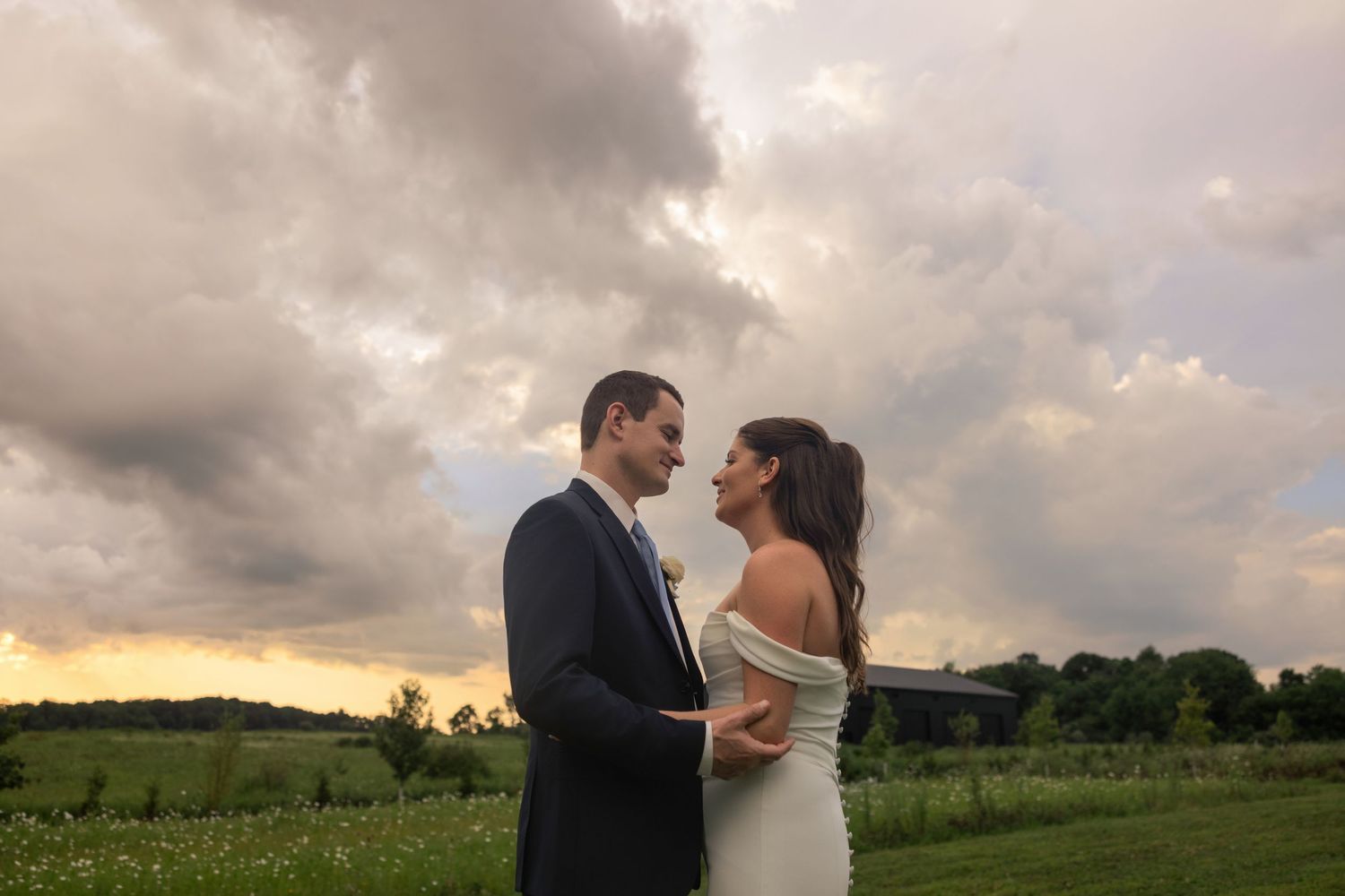 Bride and groom share a romantic moment outdoors under dramatic storm clouds at sunset in Centerburg, Ohio