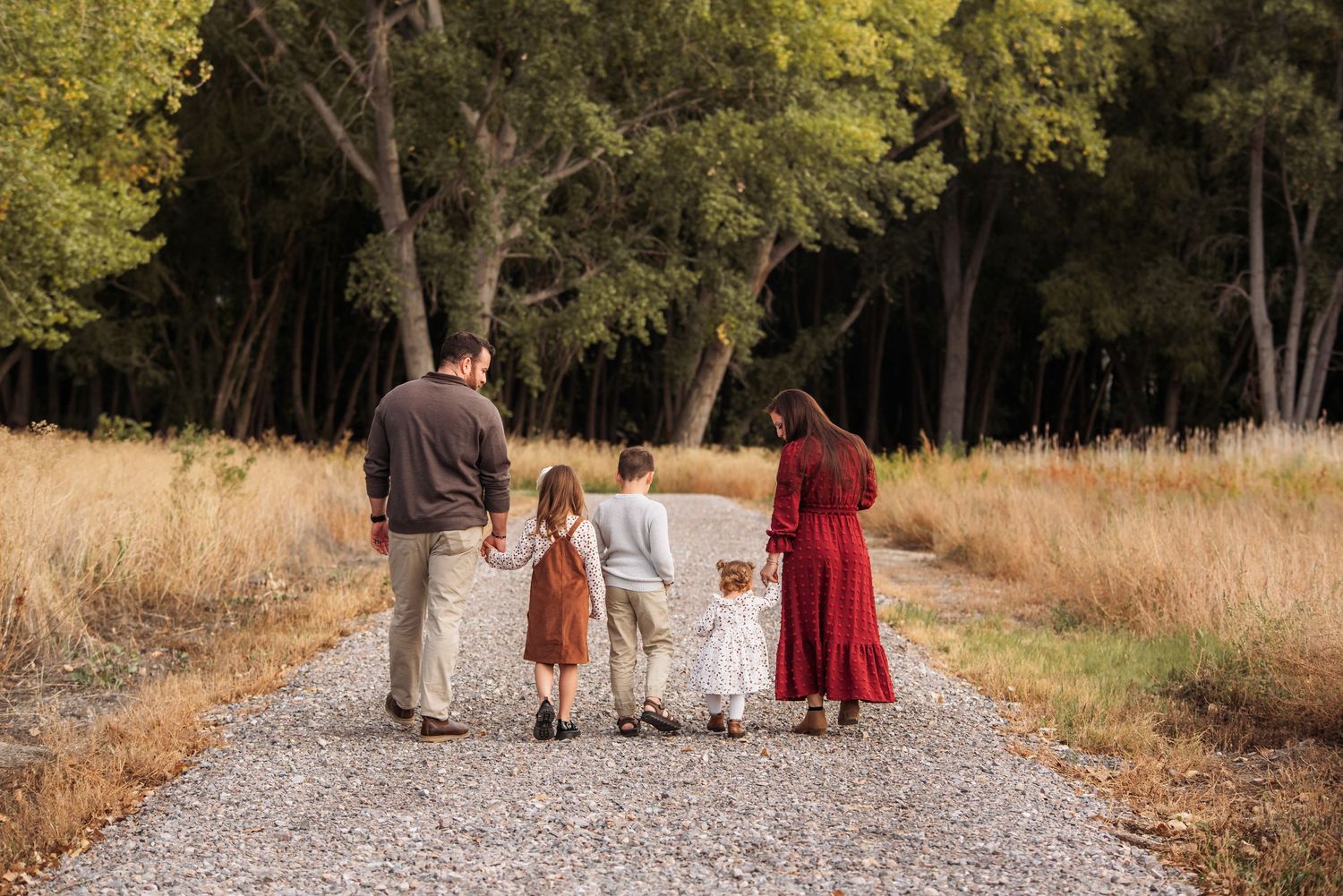 A family poses together in front of autumn foliage and mountains on a golden-hour evening.