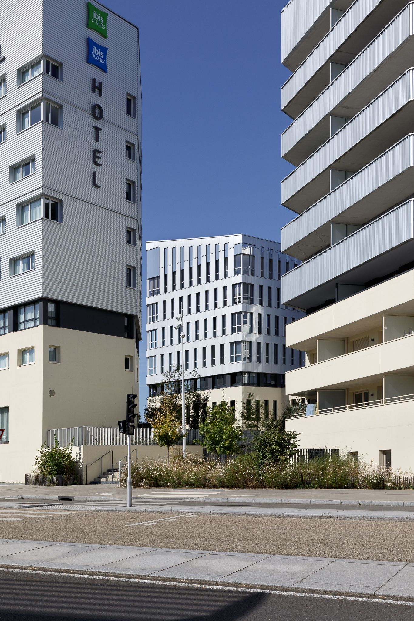 Tour de l'hôtel Ibis Styles jouxtant un immeuble résidentiel moderne doté de balcons, dans un cadre urbain.