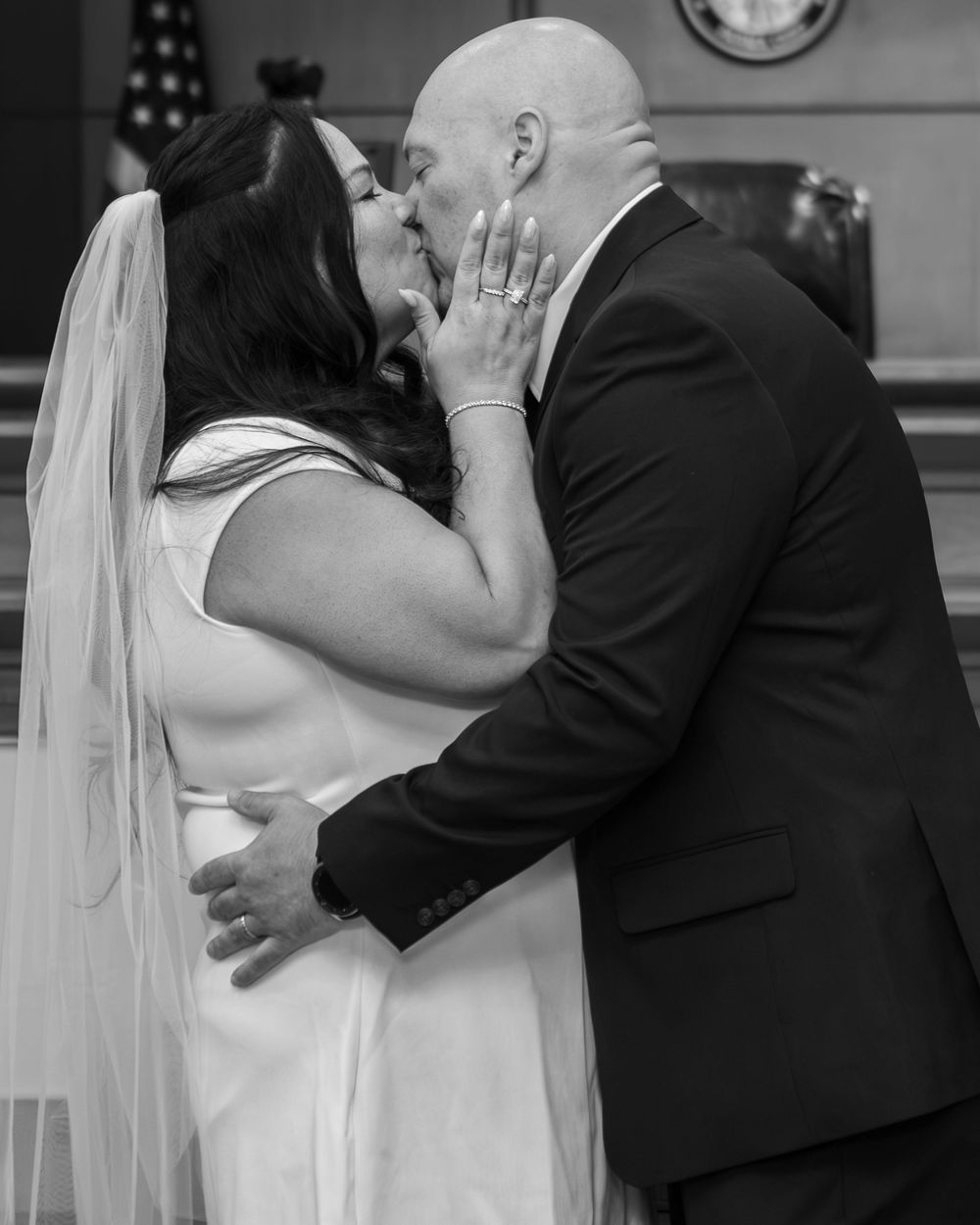 Black and white photo of a couple sharing their first kiss at a courthouse wedding ceremony.