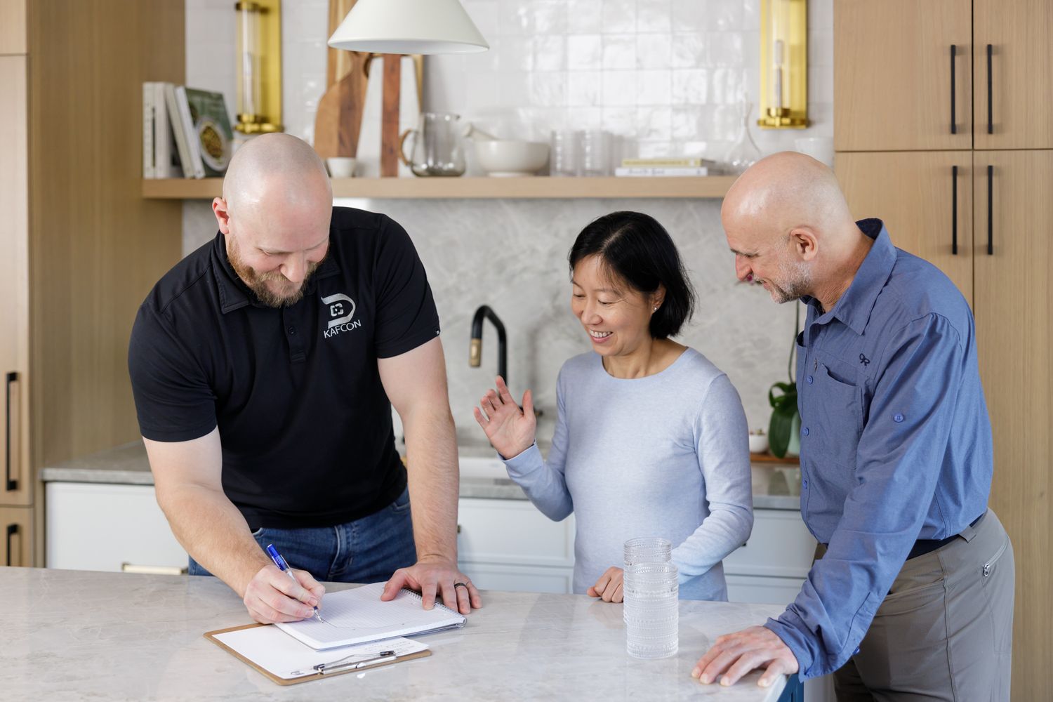 male general contractor chatting with married couple discussing design plans in kitchen for home remodel in Maple Valley, WA