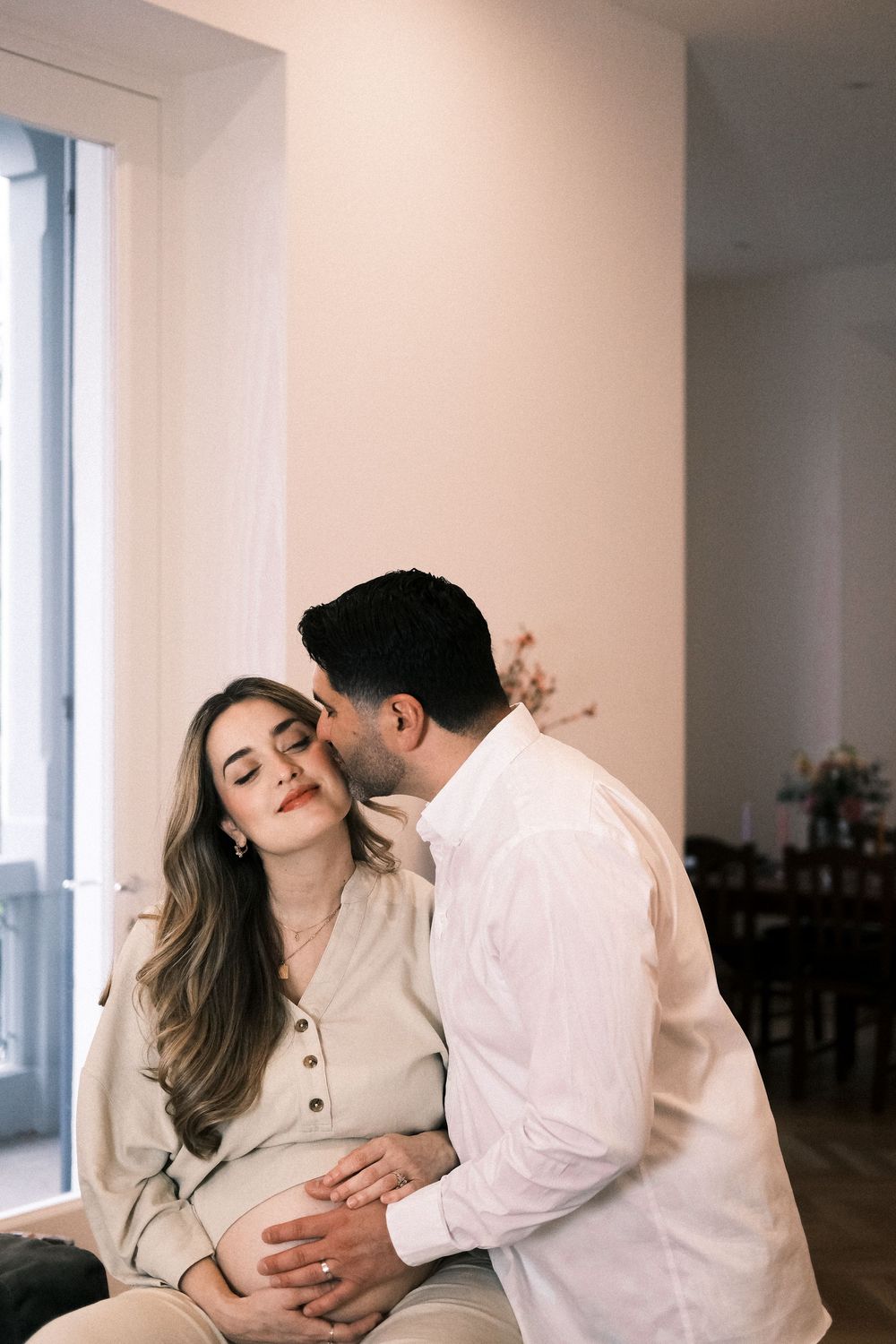 man kisses his pregnant partner's cheek during family portrait session