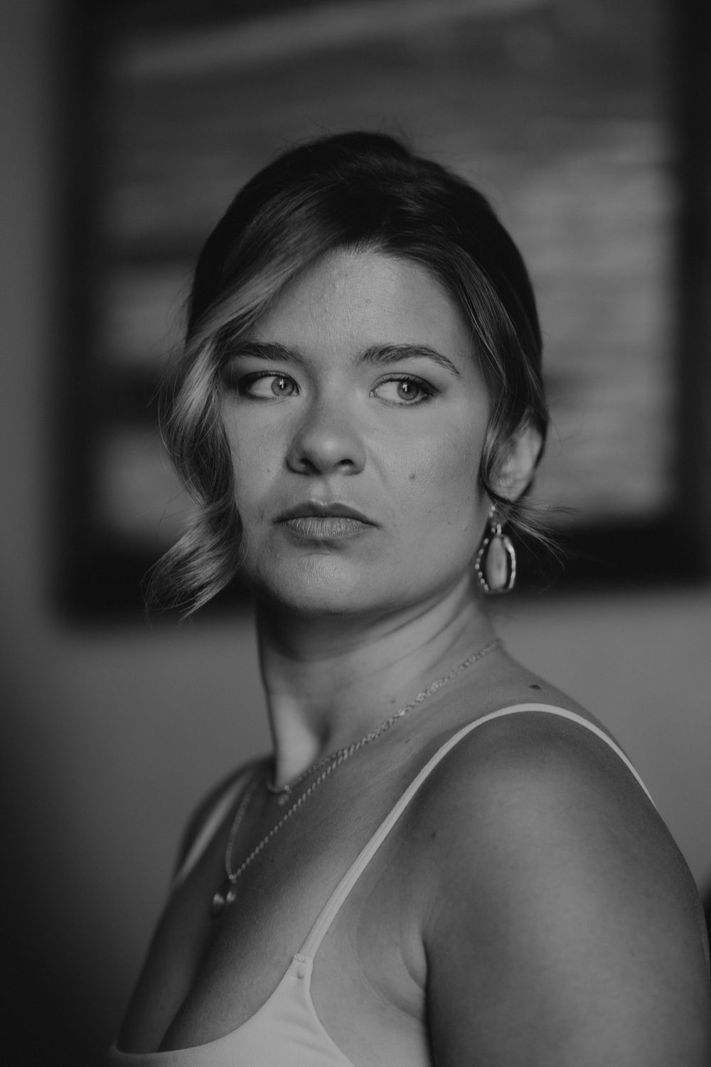 Black and white portrait of elegant woman wearing drop earrings and delicate necklace.