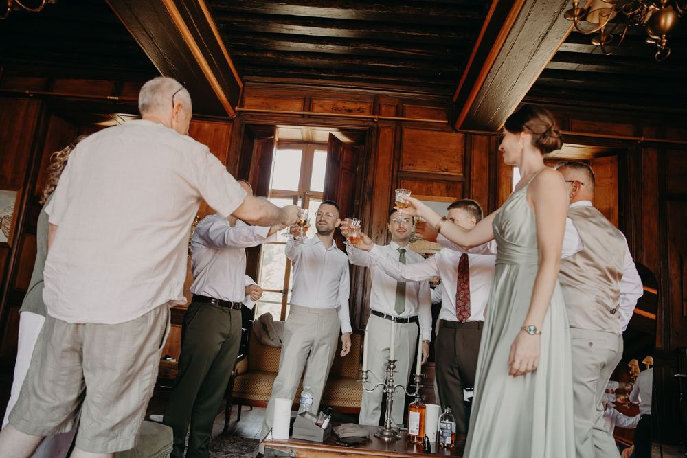 Wedding guests raising glasses in a toast inside a rustic wooden venue during a celebration.