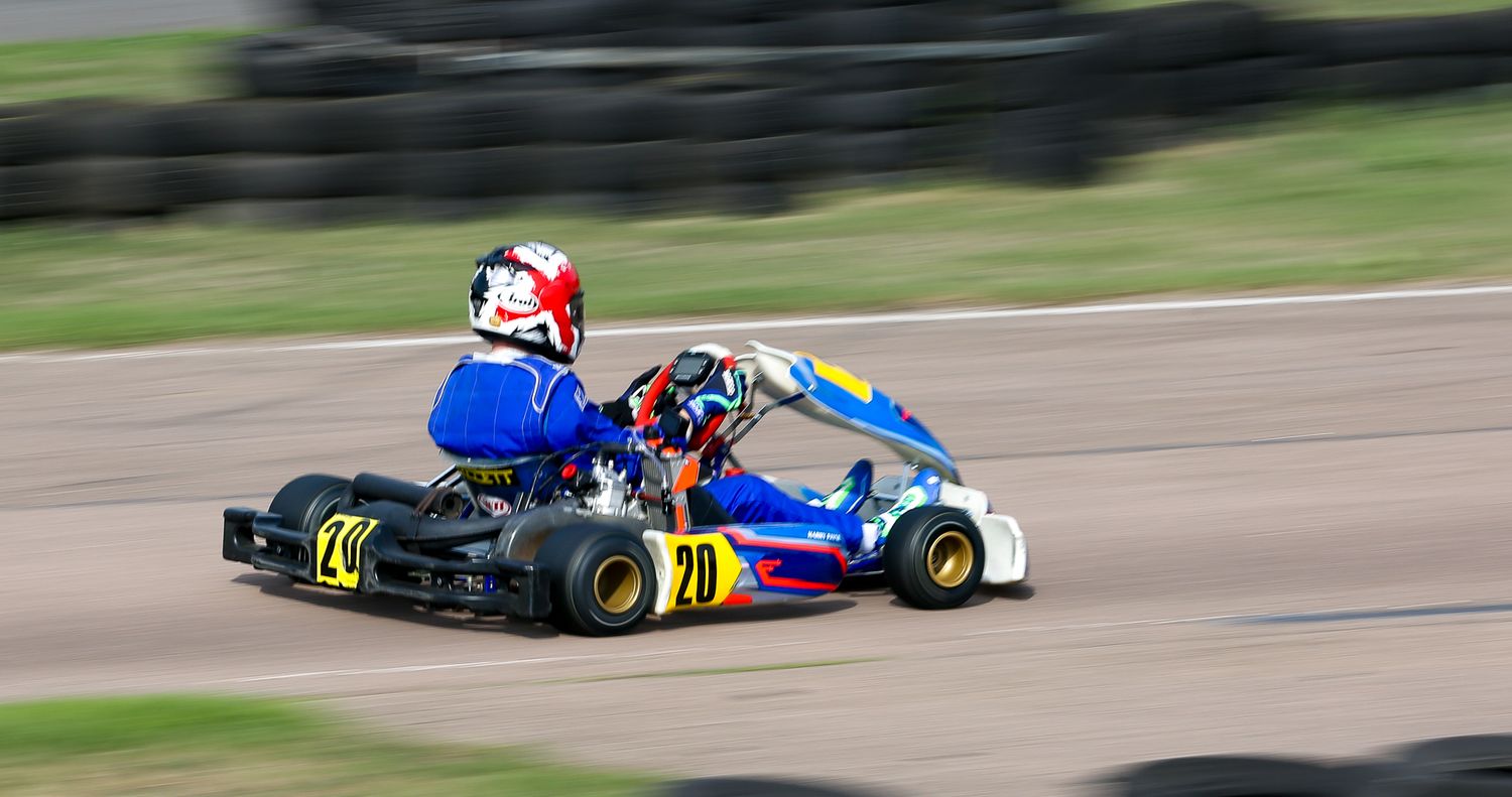 Two go-karts racing on a track, blue and white kart number 70 in foreground.