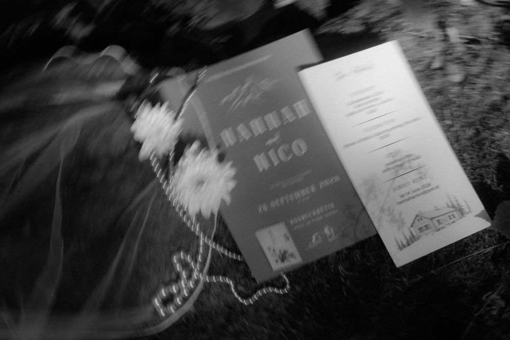 Black and white wedding program cards with floral details on decorative surface.