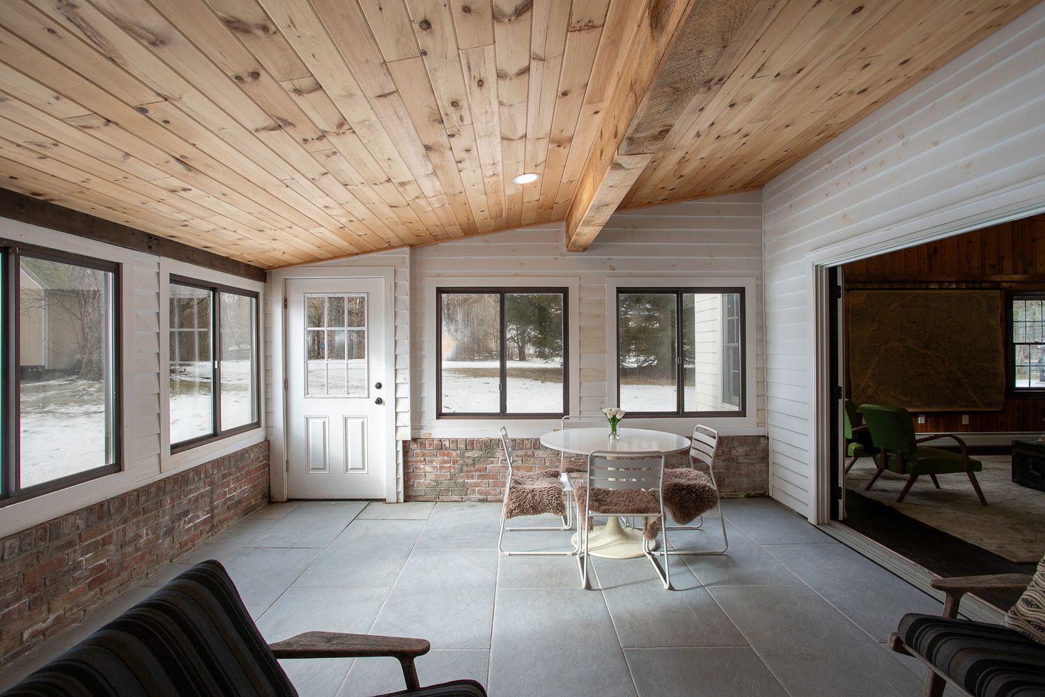 Cozy living room with hardwood floors, brick fireplace, ceiling fan, and French doors to patio.