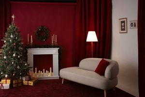 Festive living room with Christmas tree, white fireplace, candles, wreath, gifts, red curtains, and a cozy sofa with floor lamp.