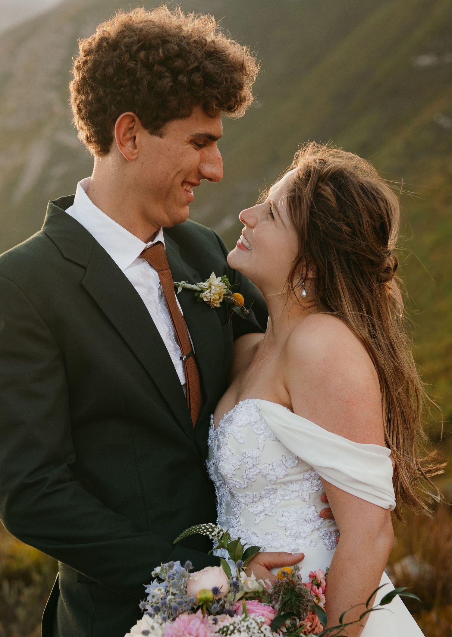 Bride and groom sharing romantic moment on mountain backdrop at golden hour outdoor wedding.