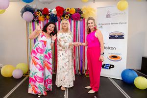 Guests posing together at the colourful photo backdrop during an awards event.