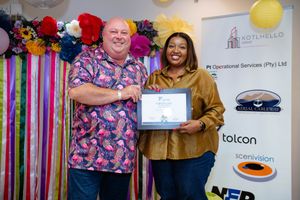 Guests posing together with an award certificate at a colourful awards ceremony.