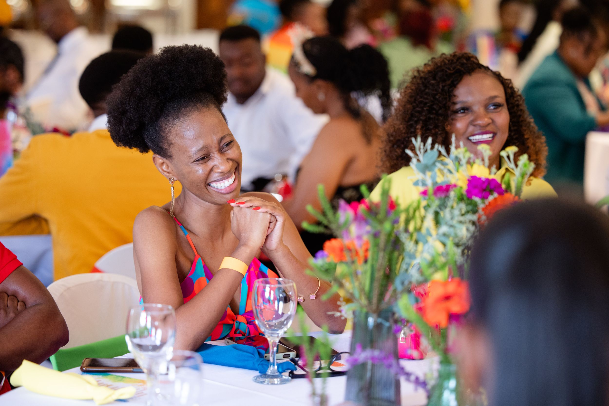 Guests socialising around colourful floral displays during an awards celebration.