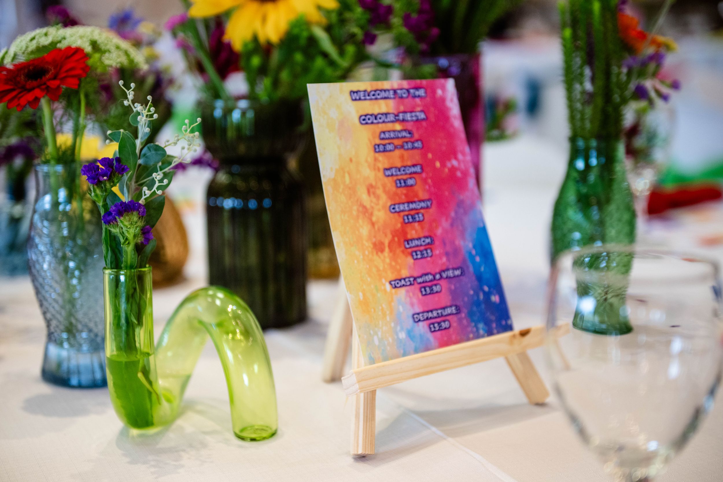 Colourful event table detail featuring flowers and a vibrant printed programme at an awards celebration.