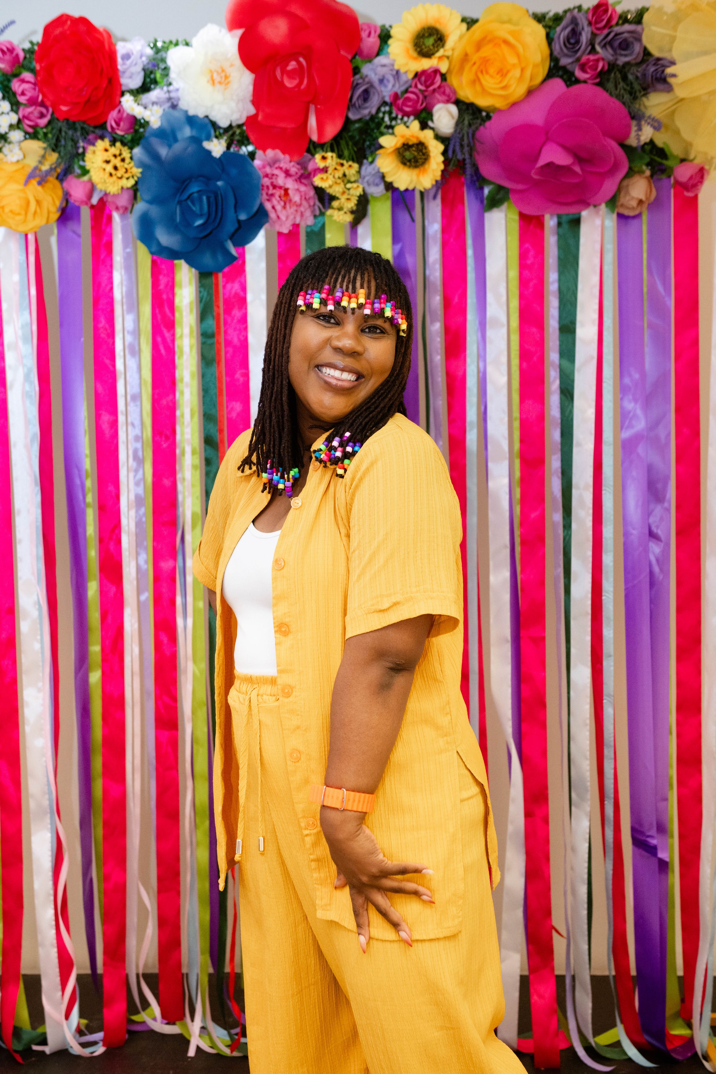 Guest posing against a colourful floral backdrop at a vibrant corporate event.