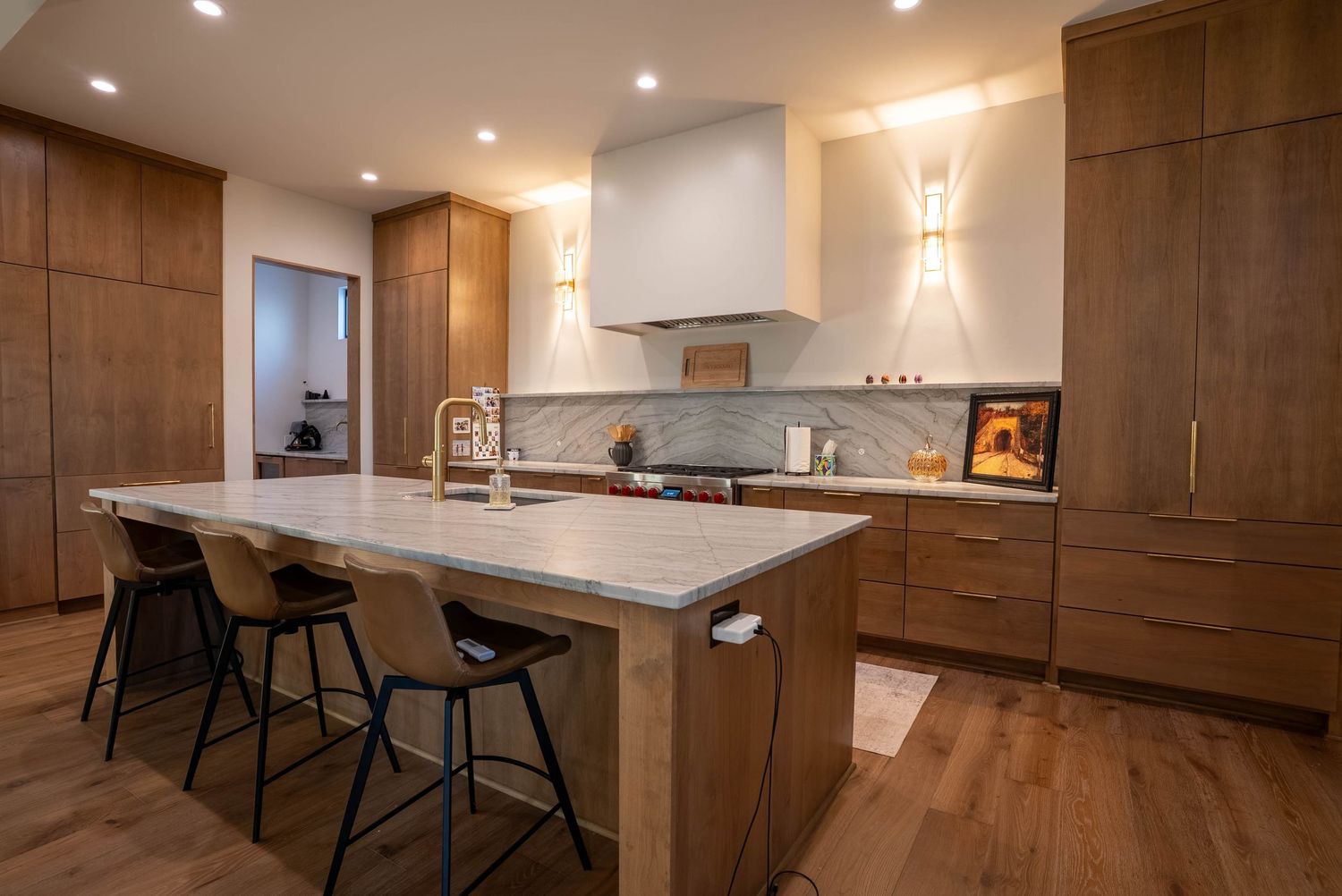 Elegant modern kitchen with walnut cabinets, marble island, bar seating, and warm wood floors.
