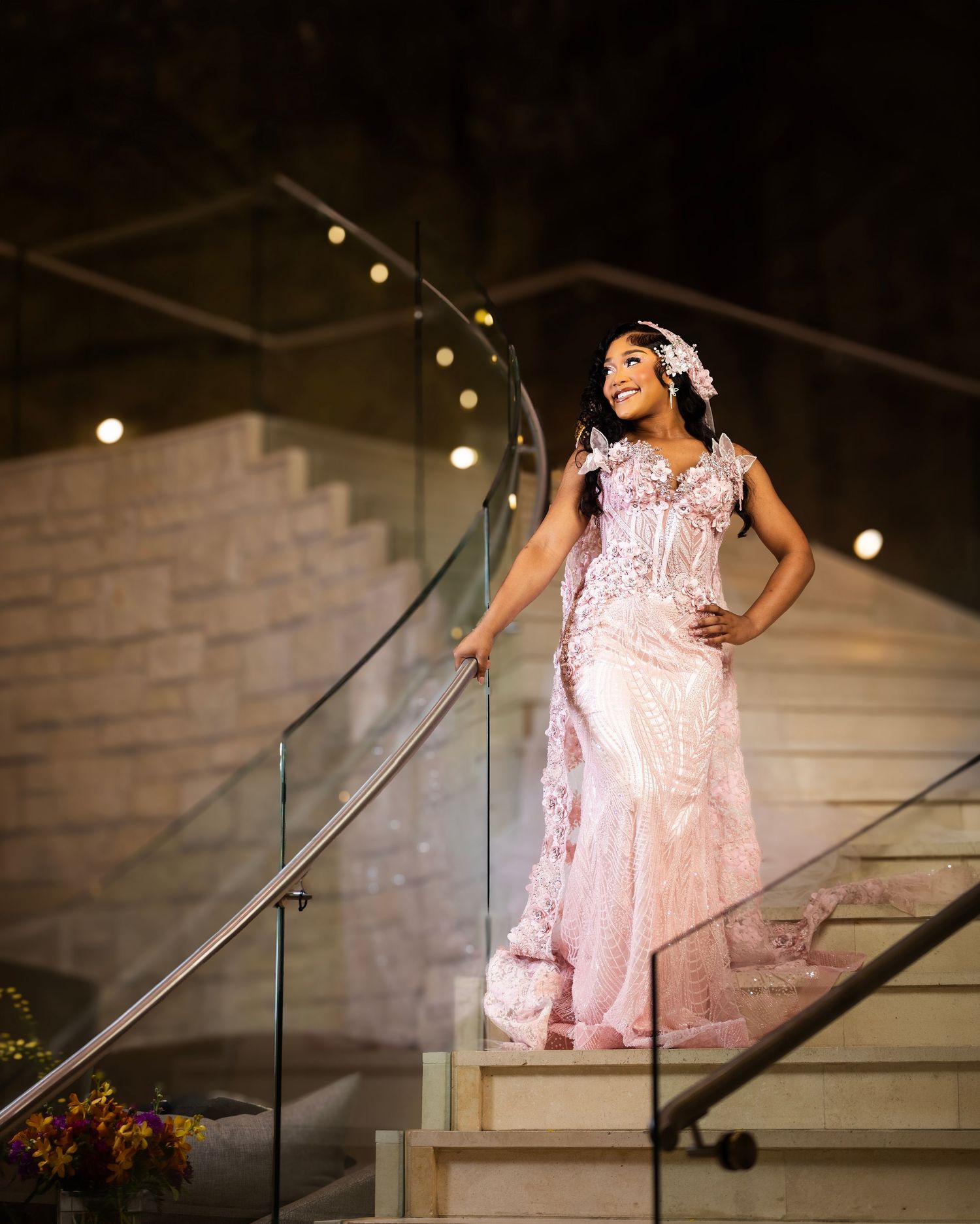 A Black couple shares a tender moment in wedding attire outdoors, bride in white gown and veil, groom in white tuxedo jacket.