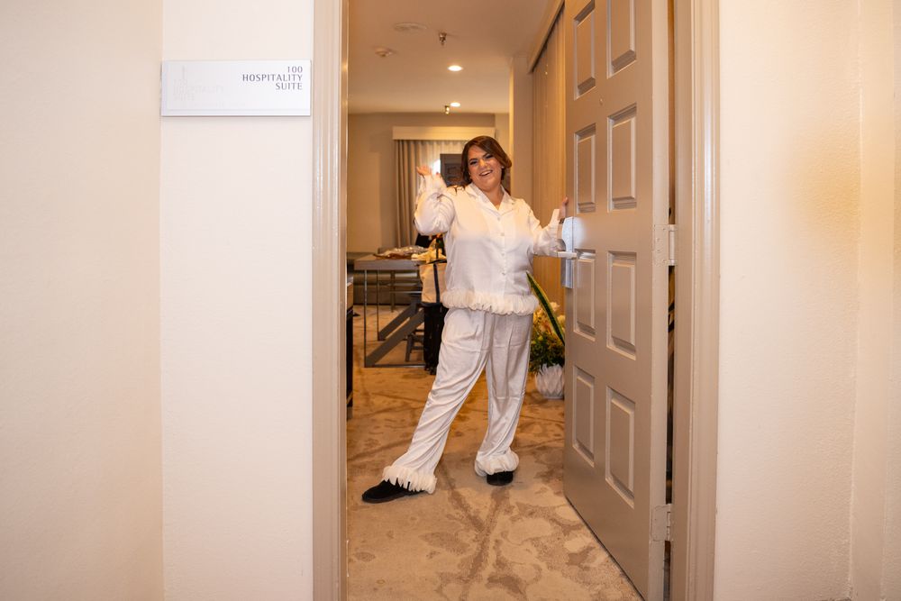 Woman in white coveralls holding a door open in a room undergoing renovation or cleaning work.
