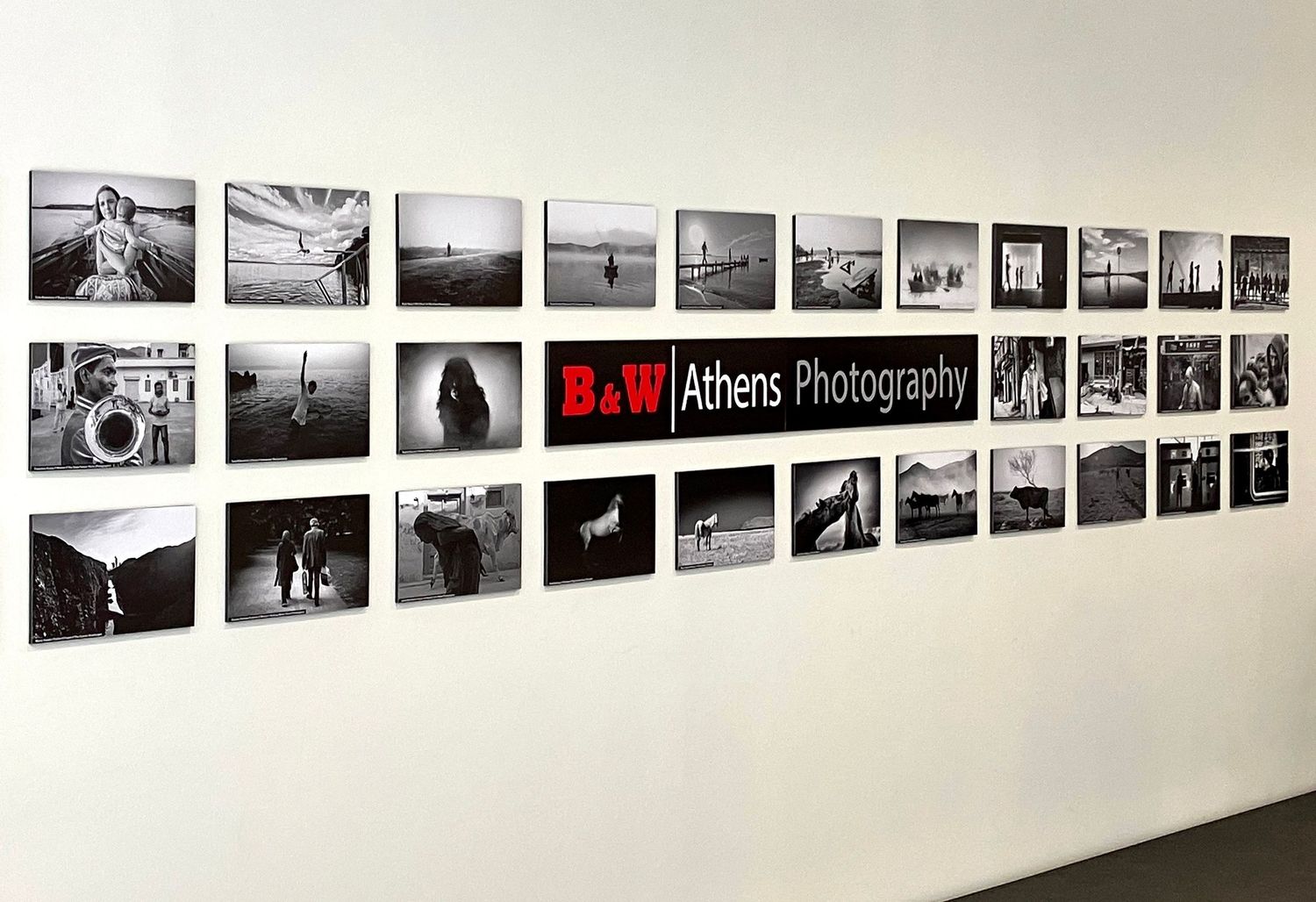 Black and white photography exhibition wall display featuring B&W Athens Photography collection in a modern gallery.