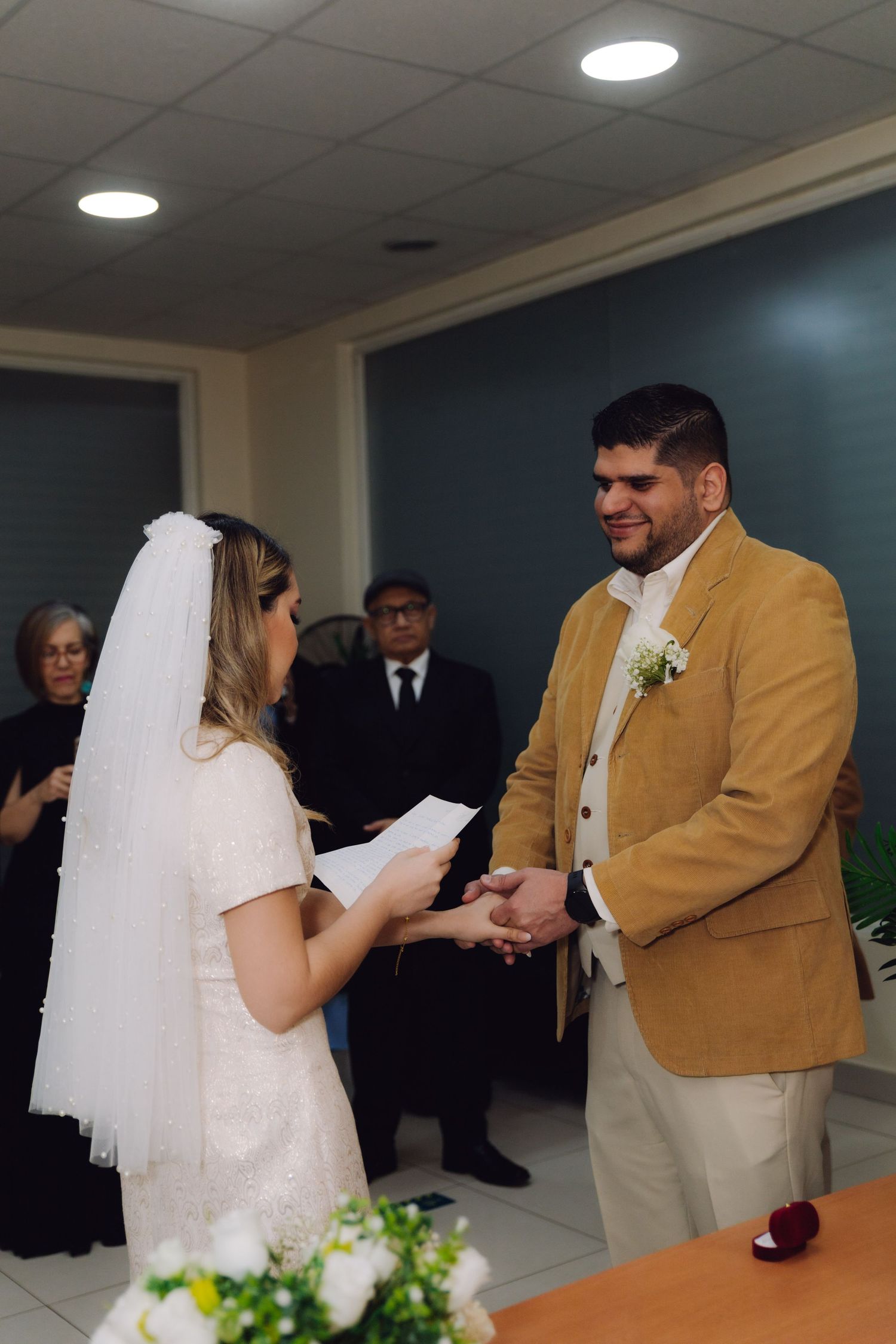 Bride reads vows while holding groom's hands during intimate civil wedding ceremony.