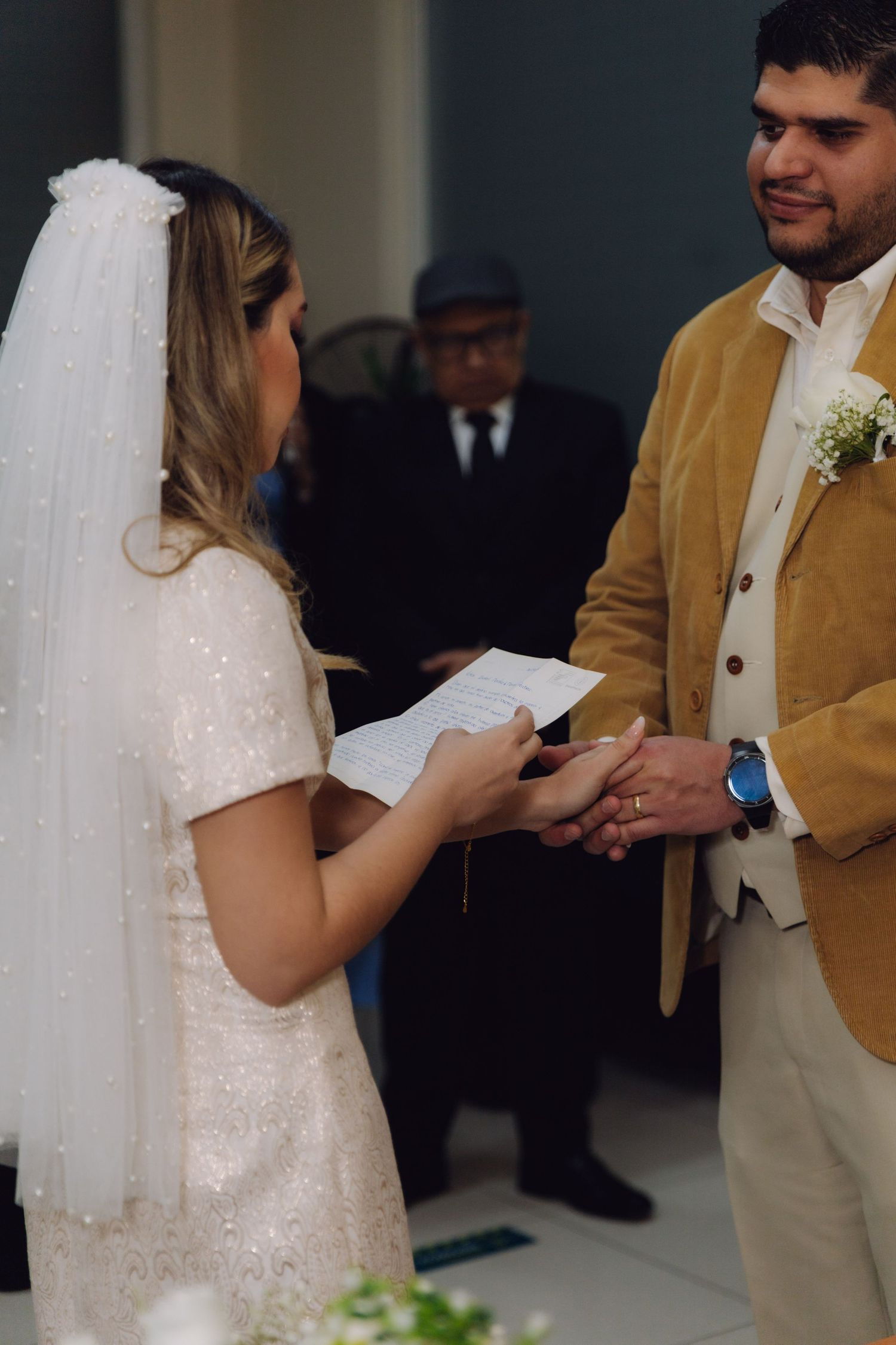 Couple exchanges rings as bride reads from paper during wedding ceremony.