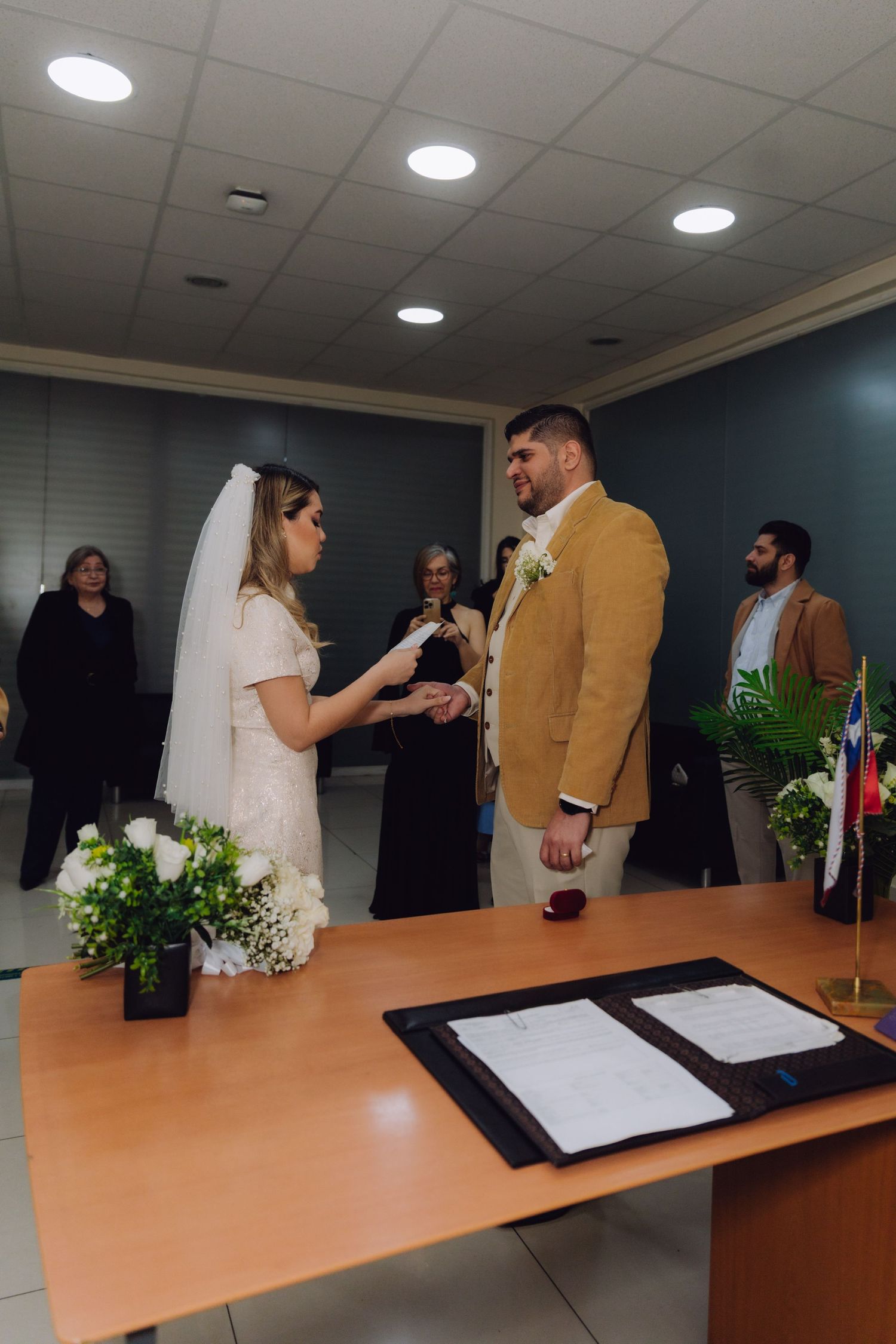 Couple exchanges vows at decorated table with white flowers during civil wedding ceremony.