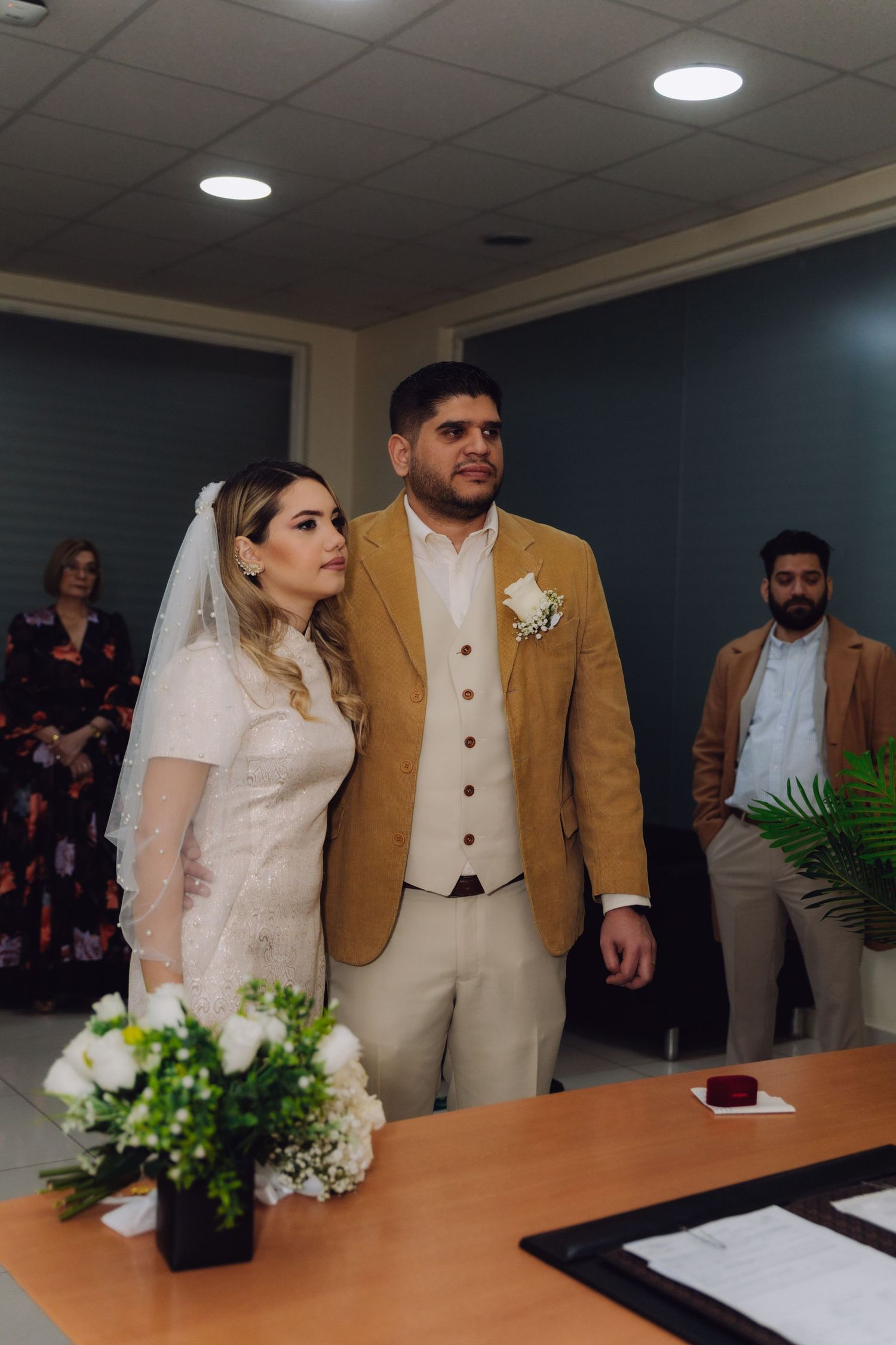 Newlywed couple stands together at altar after civil wedding ceremony with guests behind them.