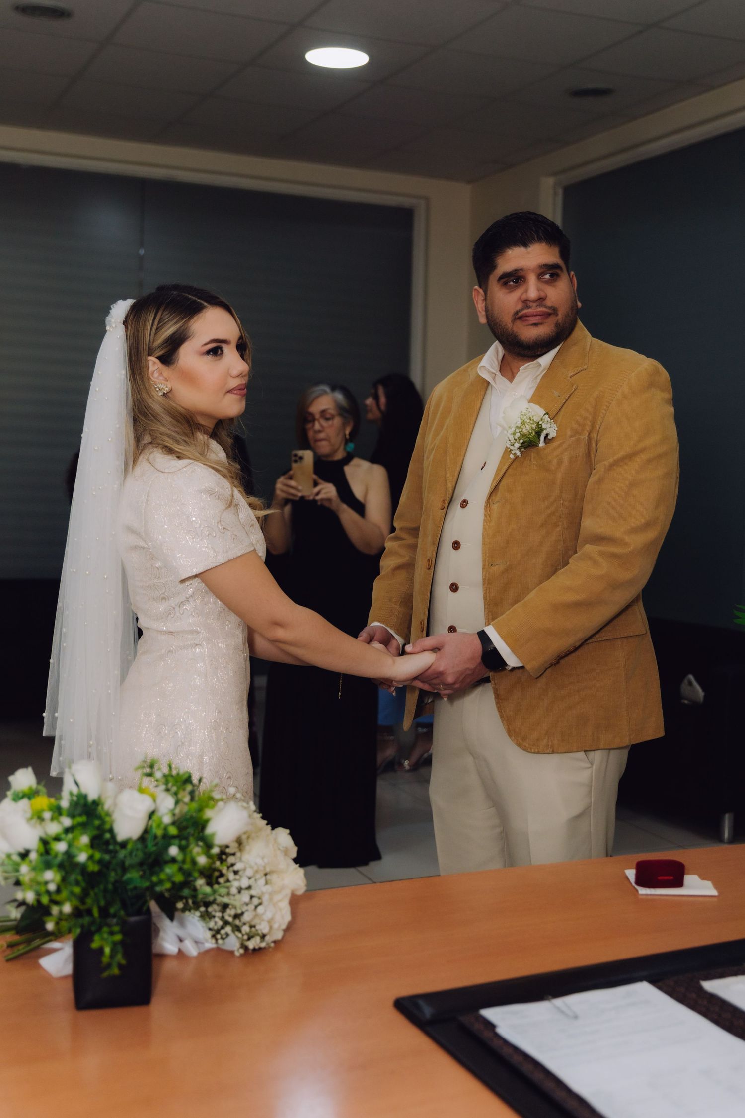 Bride and groom hold hands while posing for photo during civil wedding ceremony.