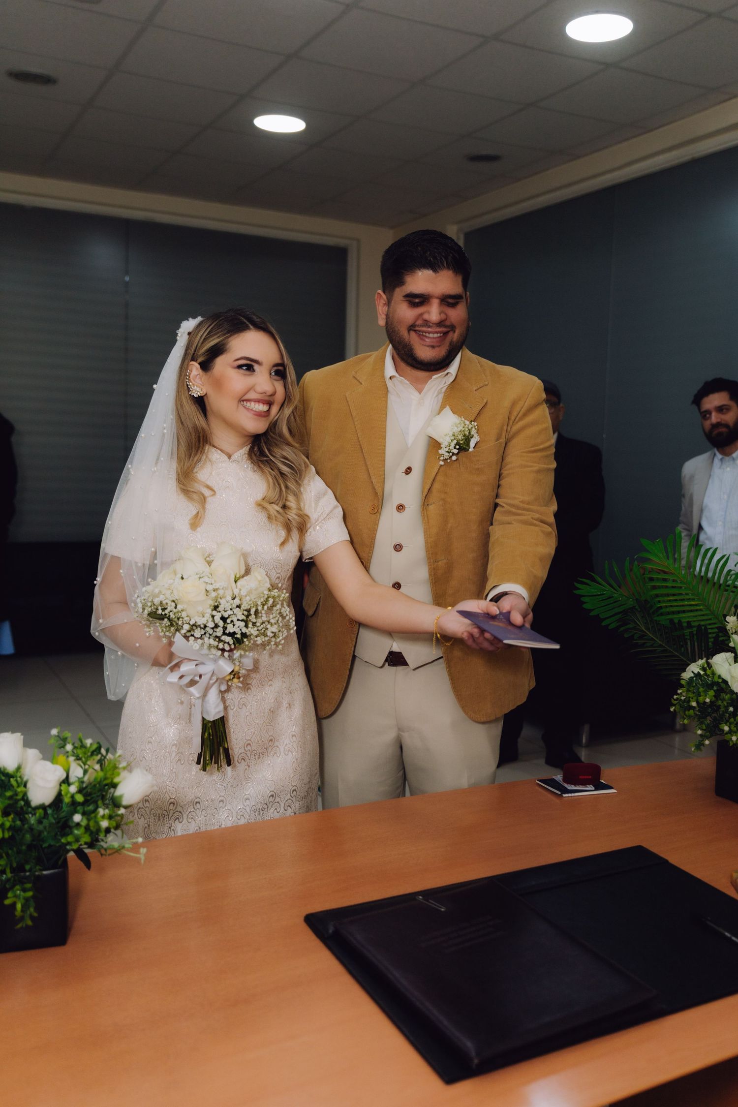 Smiling newlyweds posing together after civil wedding ceremony with bouquet.