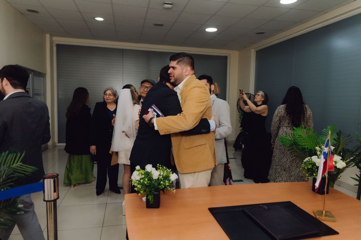 Groom embracing guest after civil wedding ceremony in official venue.